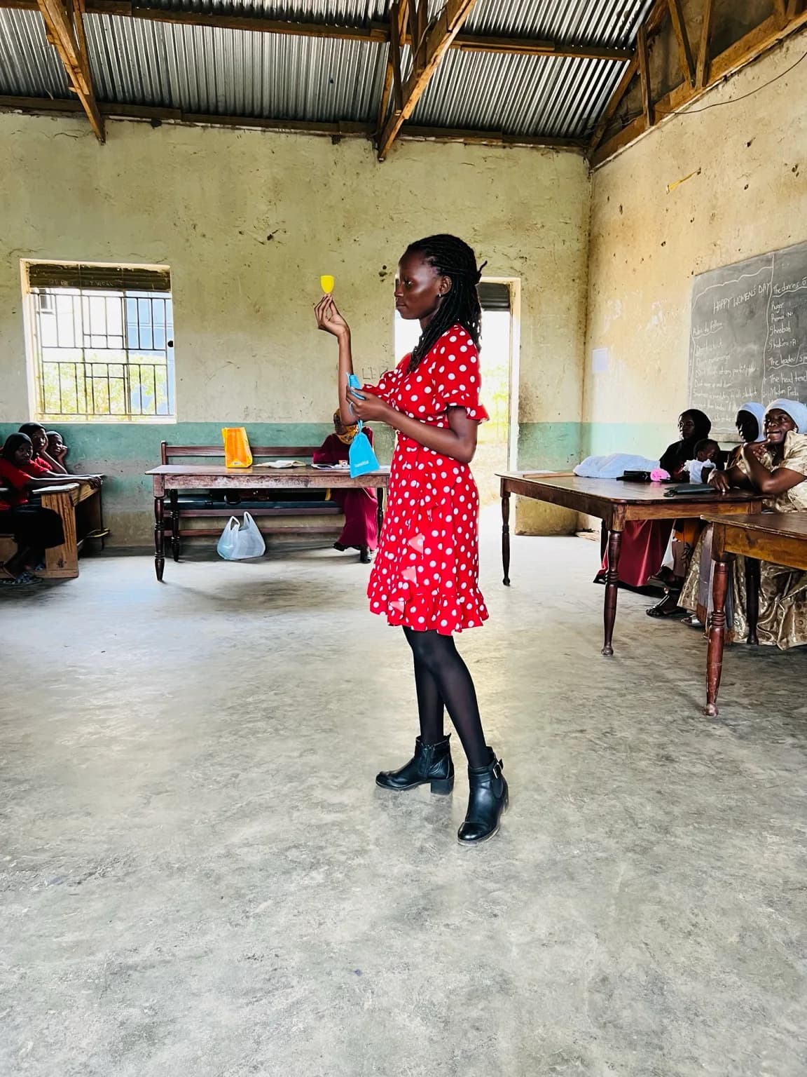 Young women in matching "SaveGirl Uganda" t-shirts and white headscarves gather during a mentorship and menstrual health education session.